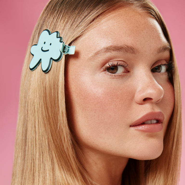 Woman with a cloud-shaped hair clip on a pink background