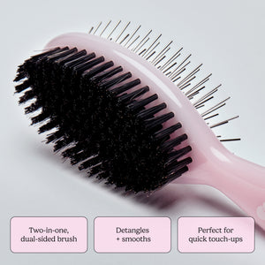 Close up of pink dual sided brush showing metal pins along the edge and densely packed bristles