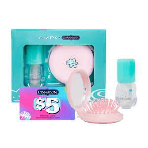 Maeve Cinnamon travel beauty set featuring a turquoise box, a pink round mirror, a pink hairbrush, and two teal/cyan bottles, displayed on a clean white background.