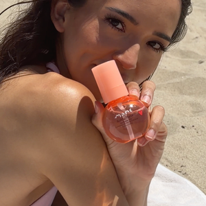 Woman holding a pink bottle on a sandy background