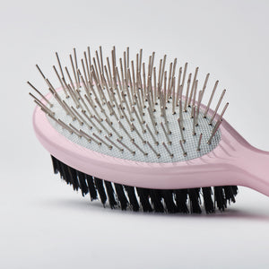 Close up of a pink travel sized dual-sided brush with metal detangling pins