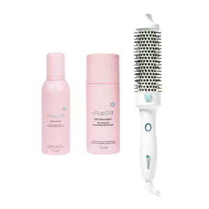 A hair styling set on a white background, featuring a pink hair dryer, a pink hair dryer attachment, a pink hair oil bottle, and a white round hair brush with black bristles.