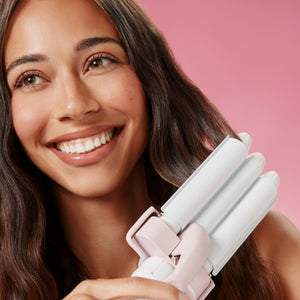 Woman using Triple Ripple Mini Waver against pink background