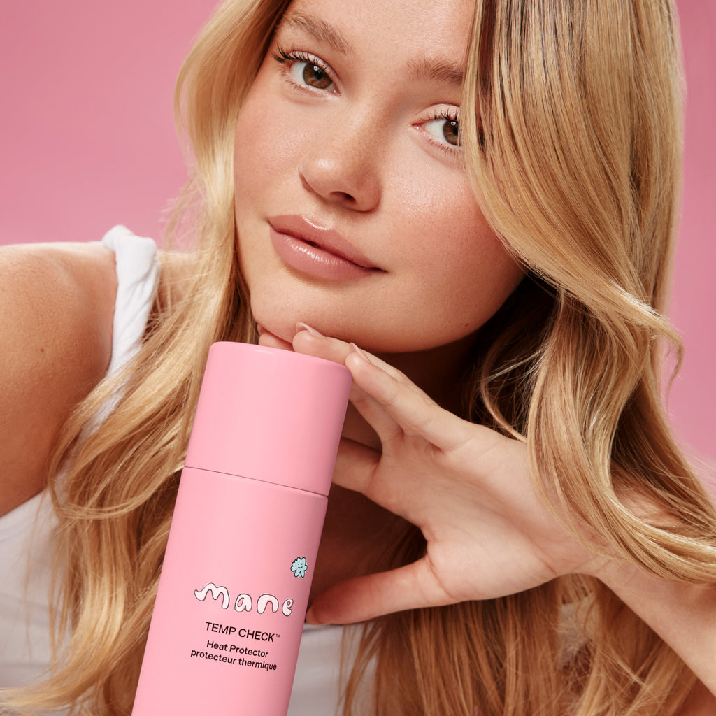 Woman holding a pink bottle labeled 'Mane' against a pink background