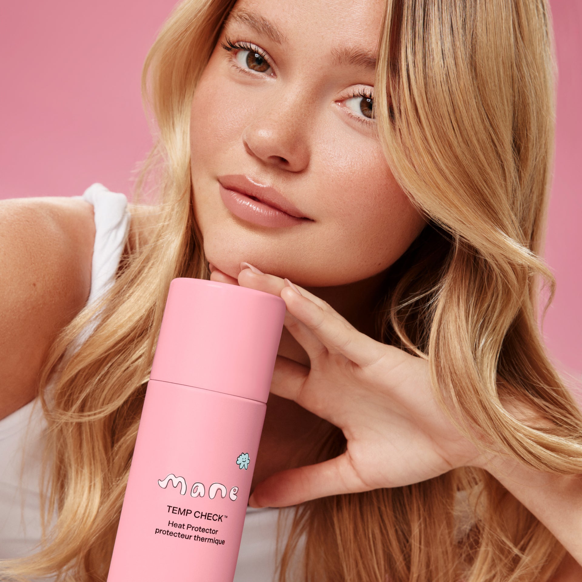 Woman holding a pink bottle labeled 'Mane' against a pink background