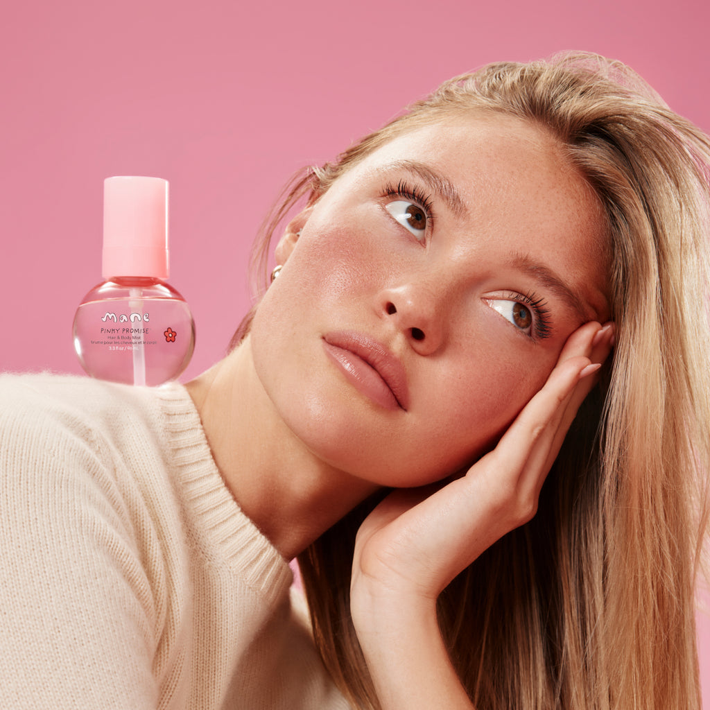 Woman with a pink background and a bottle of skincare product.