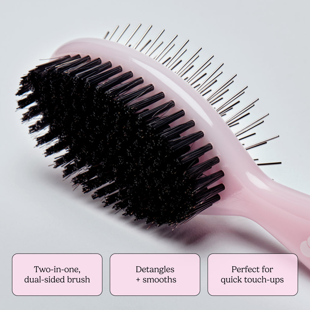 Pink hairbrush with black bristles on a light gray background