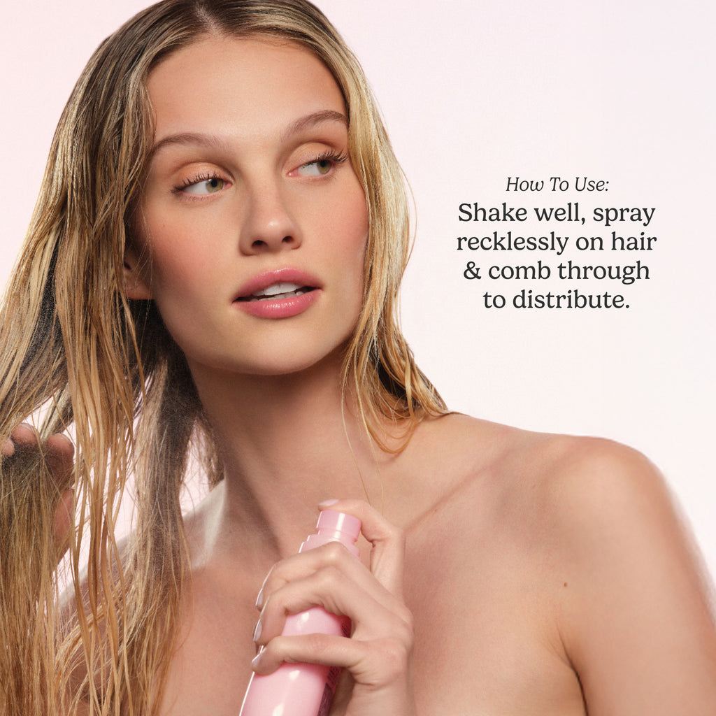 Woman holding a pink hair product with text on how to use it against a light pink background