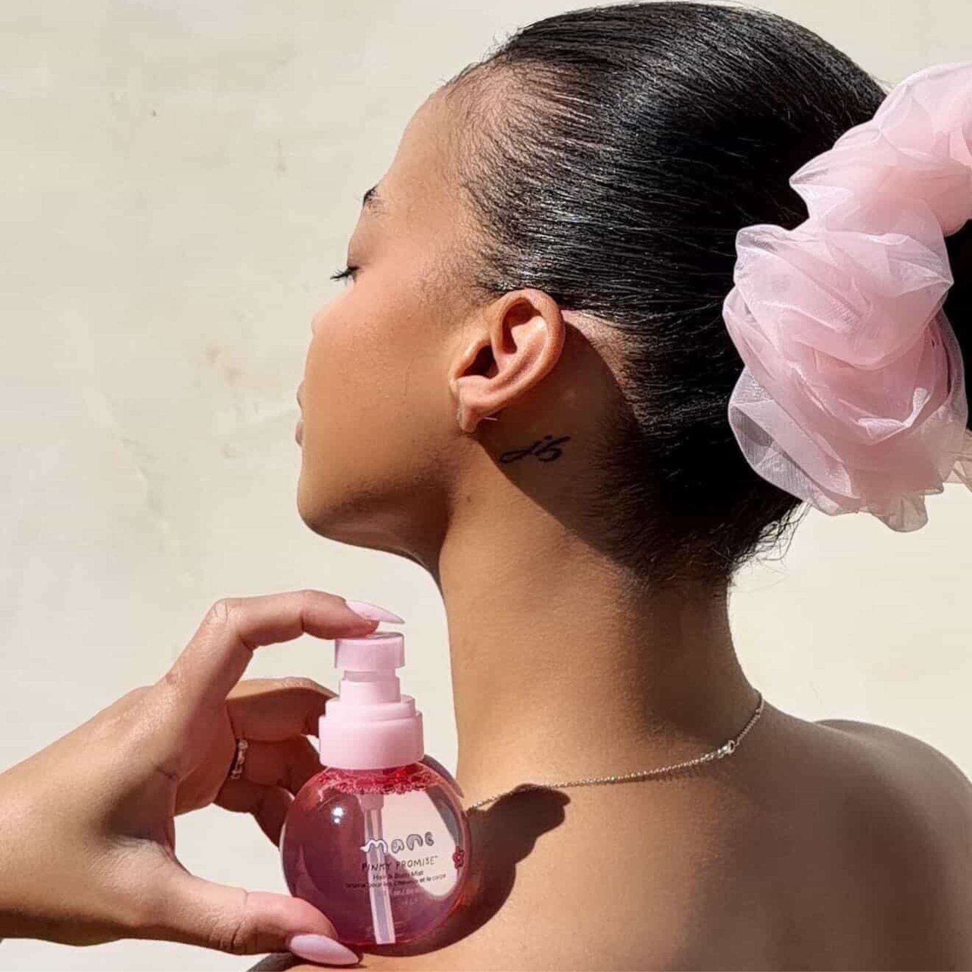Woman holding Pinky Promise hair and body mist on shoulder