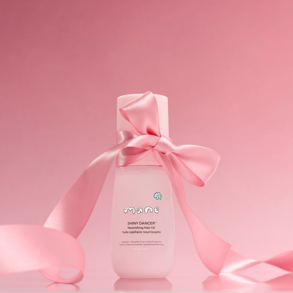 Bottle of 'Shiny Dancer' nourishing hair oil with a pink ribbon tied in a boy on a pink background