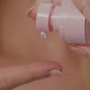 video of hands trying pink bottle of nourishing hair oil 