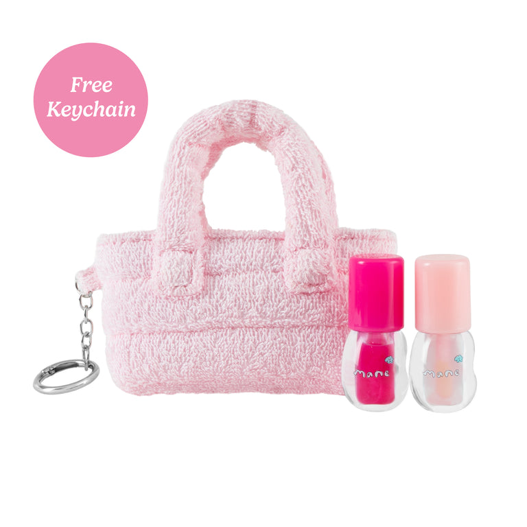 Pink fuzzy handbag with two nail polishes and a keychain on a white background